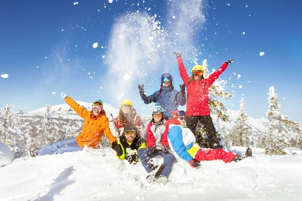 A group of friends in ski gear throwing snow
