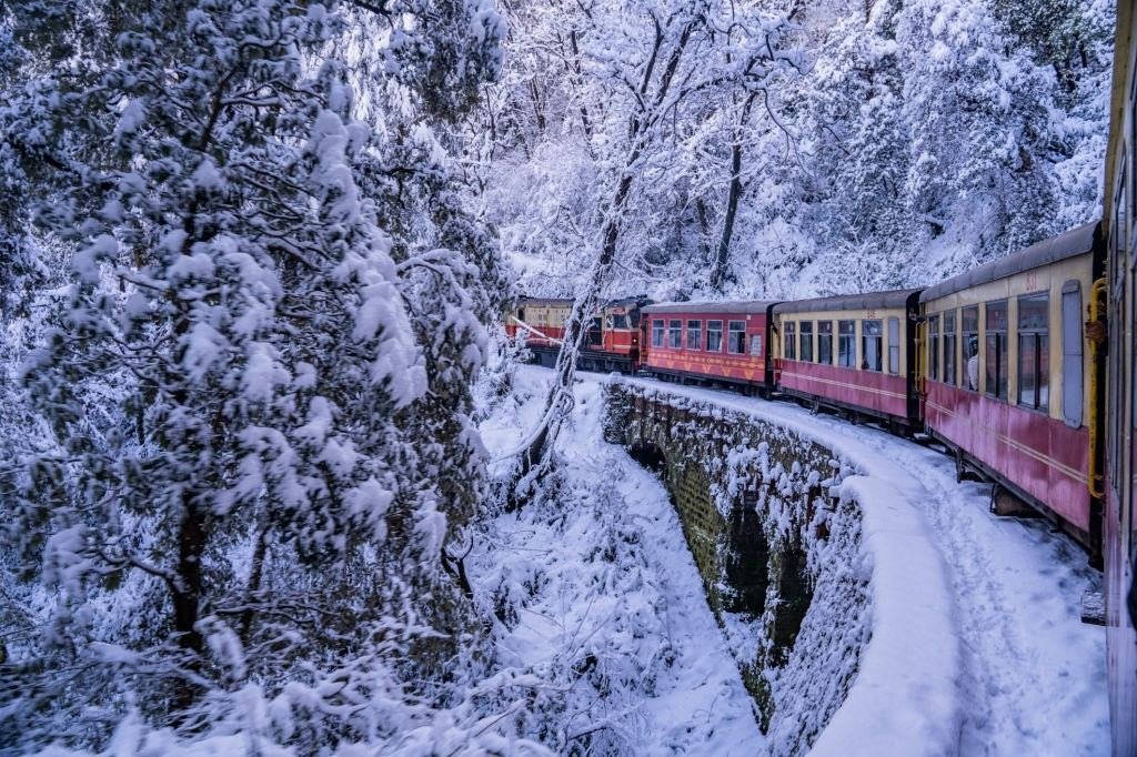 The Kalka-Shimla toy train crossing a stone bridge in snow