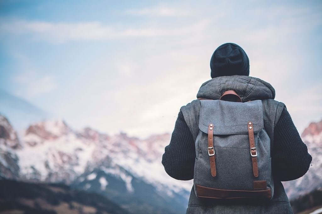 A traveller with a backpack looking at snow-capped mountains